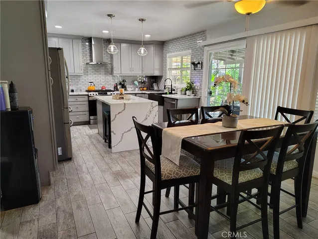 a kitchen with stainless steel appliances kitchen island granite countertop a table chairs and a refrigerator