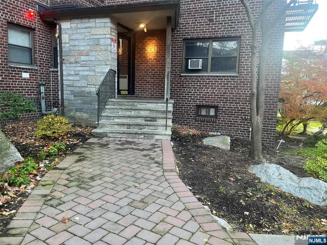 a brick house with a small yard and large tree