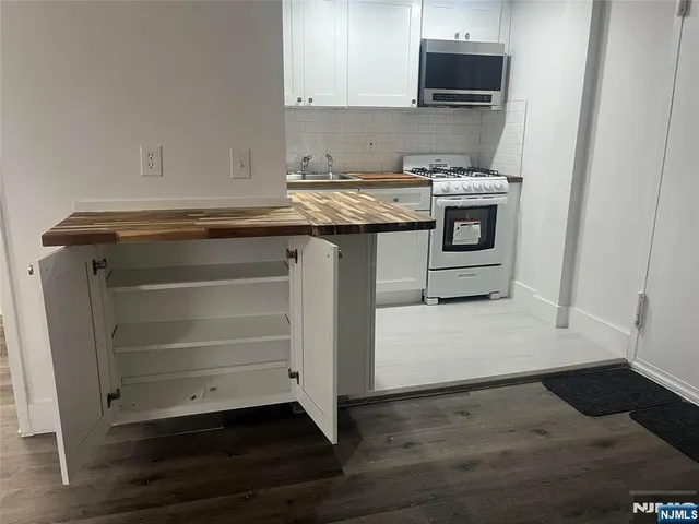 a kitchen with stainless steel appliances granite countertop a stove a sink and a microwave