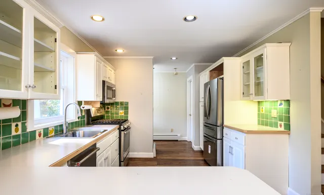 a kitchen with stainless steel appliances granite countertop a refrigerator a stove and a sink with wooden floor