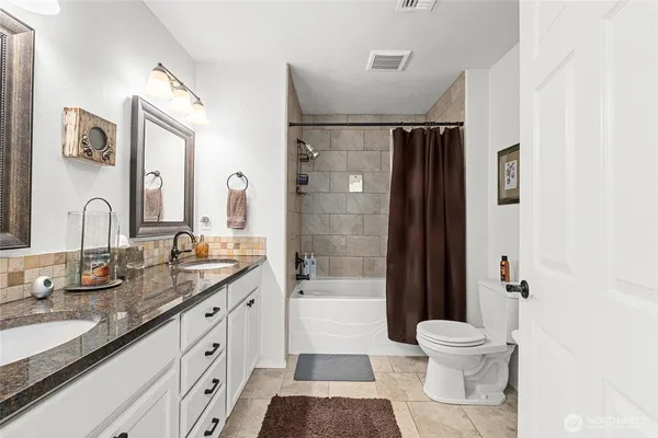 a bathroom with a double vanity sink toilet and shower