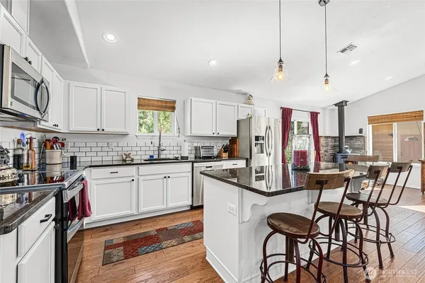 a kitchen with stainless steel appliances granite countertop a stove a sink dishwasher and a refrigerator with wooden floor