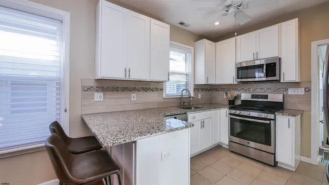 a kitchen with granite countertop a stove sink and microwave