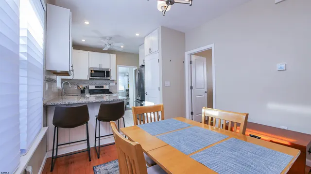 a kitchen with stainless steel appliances a dining table chairs stove refrigerator and cabinets