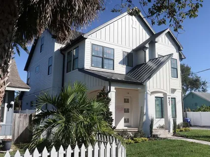 a view of a house with a large windows and flower plants with wooden fence