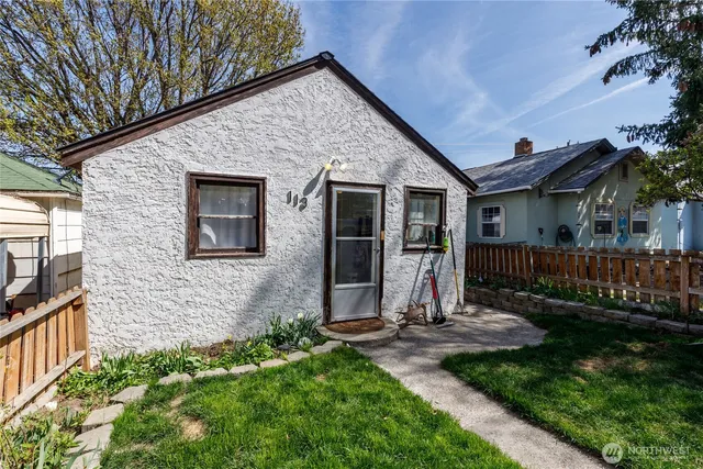 a view of a house with brick walls and a yard with plants
