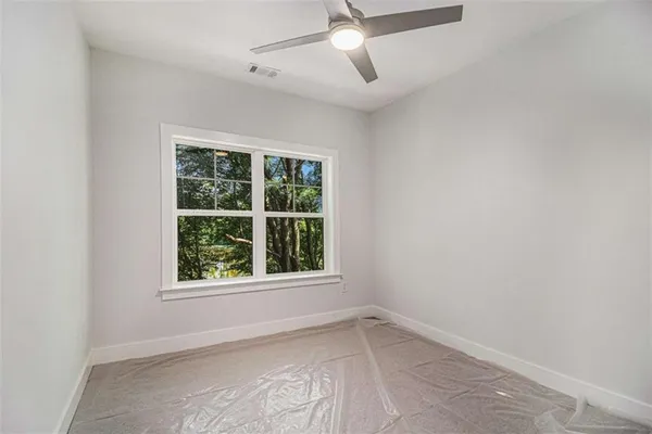 an empty room with a window and ceiling fan