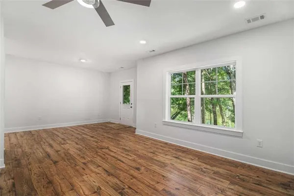 a view of an empty room with wooden floor and a window