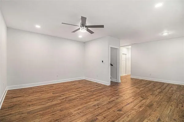 an empty room with wooden floor fan and windows