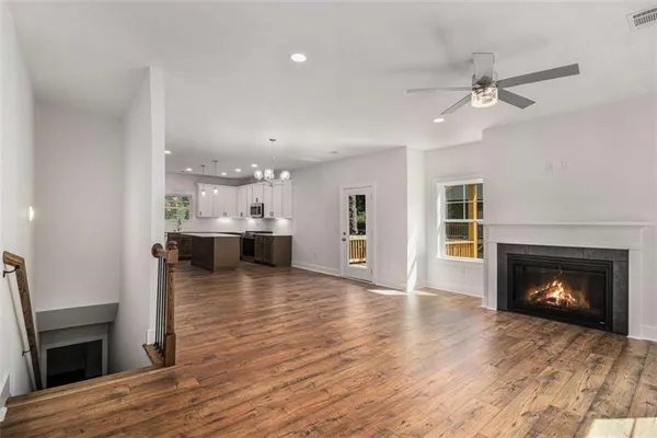 a view of a kitchen and an empty room with wooden floor and a fireplace
