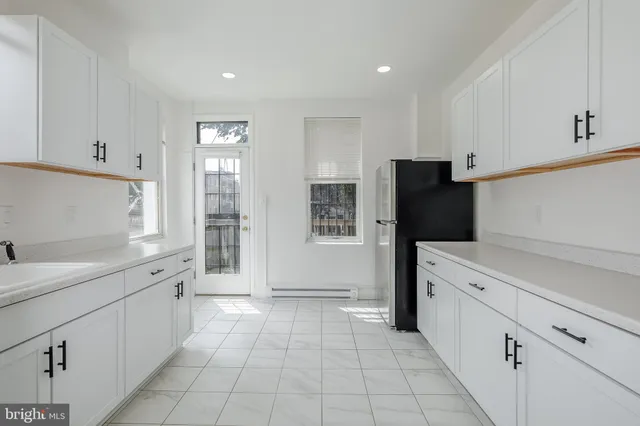 a kitchen with white cabinets and refrigerator