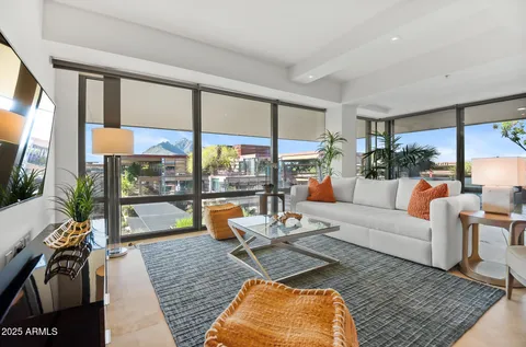 a living room with furniture a flat screen tv and a floor to ceiling window