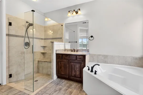 a bathroom with a tub a sink shower and mirror
