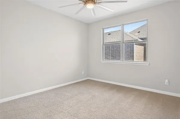 an empty room with a window and a chandelier fan