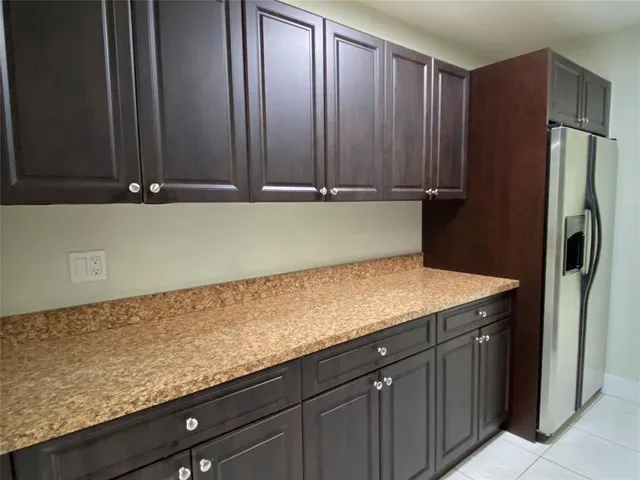 a kitchen with granite countertop a refrigerator and cabinets