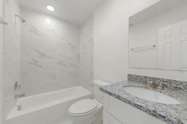 a bathroom with a granite countertop sink toilet and shower