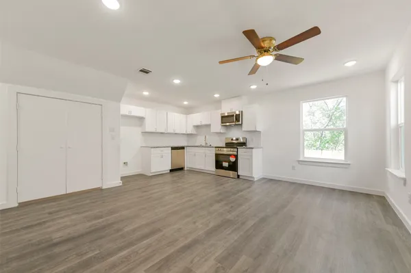 a view of an empty room with kitchen appliances and a window