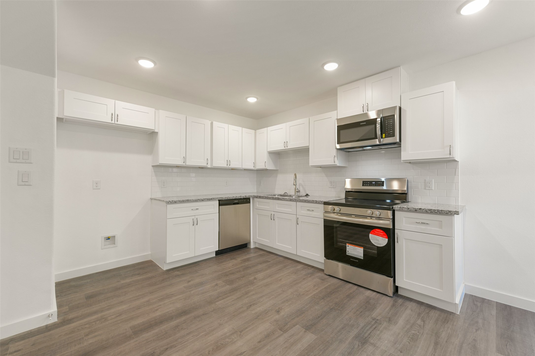 8713 Southwark Street, Unit B Houston, TX 77028 - Photo 5 of 17 a kitchen with stainless steel appliances white cabinets a sink a stove a microwave and wooden floors