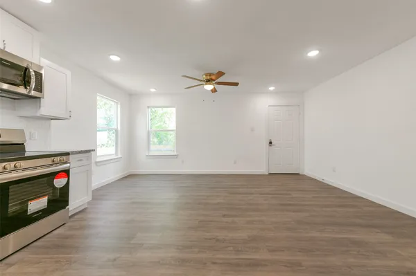 a view of an empty room with a window and a kitchen