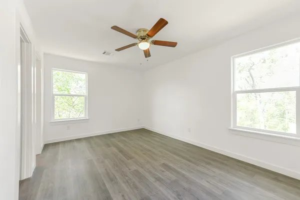 a view of empty room with wooden floor and fan