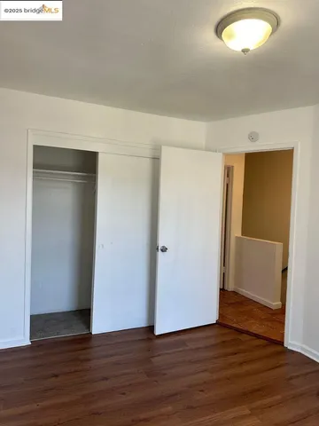 a view of an empty room with wooden floor and closet
