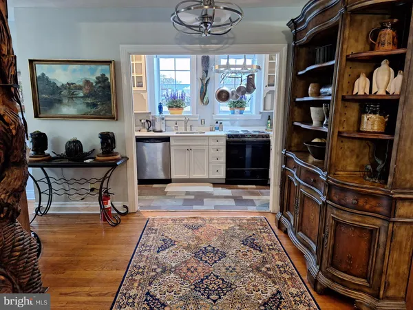 a living room with stainless steel appliances furniture a rug and a book shelf