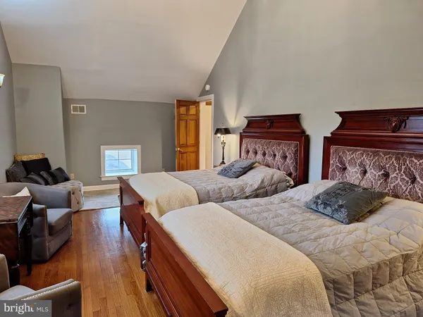 a bedroom with two beds and wooden floor
