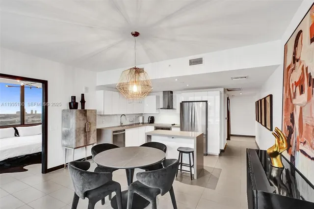 a kitchen with stainless steel appliances a dining table chairs and a refrigerator