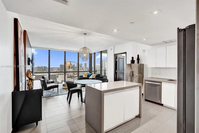 a open kitchen with stainless steel appliances kitchen island a stove a refrigerator a sink dishwasher and a dining table with the kitchen view