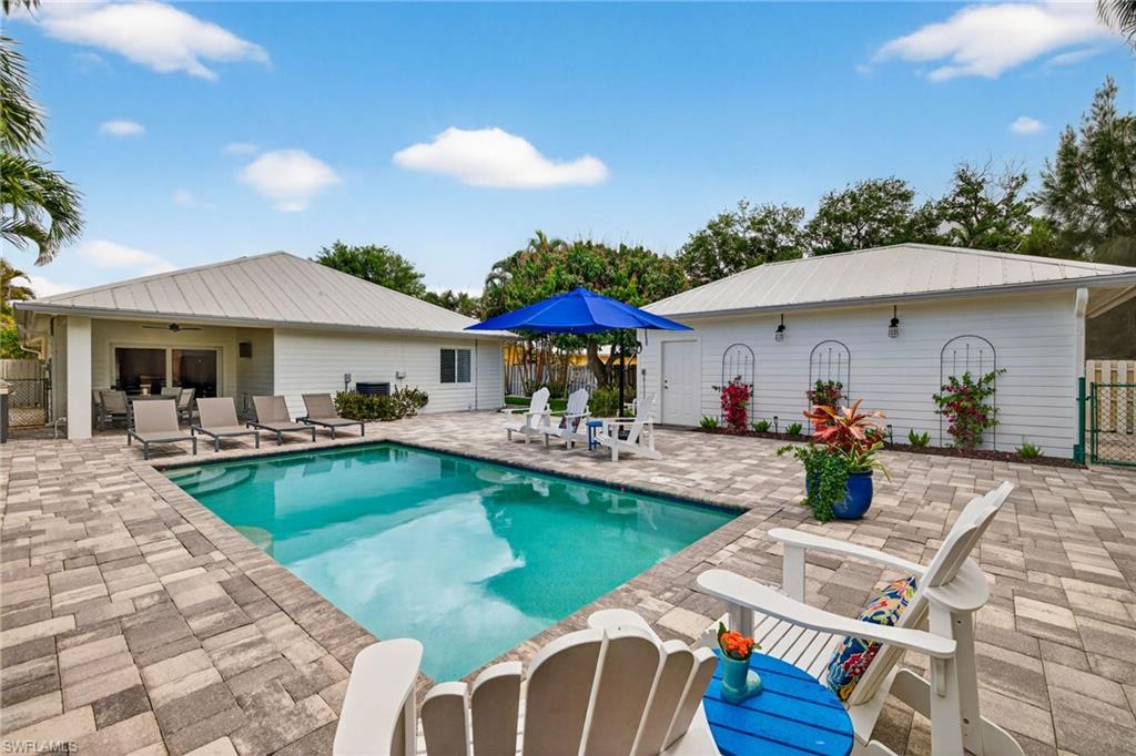 740 5th Avenue North Naples, FL 34102 - Photo 37 of 43 a view of a swimming pool with lawn chairs under an umbrella