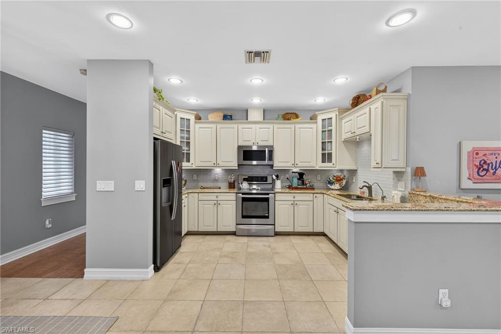 740 5th Avenue North Naples, FL 34102 - Photo 8 of 43 a kitchen with stainless steel appliances granite countertop a refrigerator sink and cabinets
