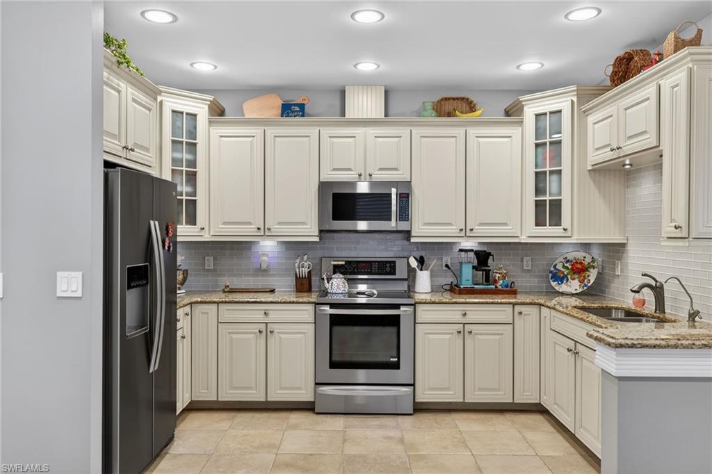 740 5th Avenue North Naples, FL 34102 - Photo 9 of 43 a kitchen with stainless steel appliances granite countertop white cabinets and sink