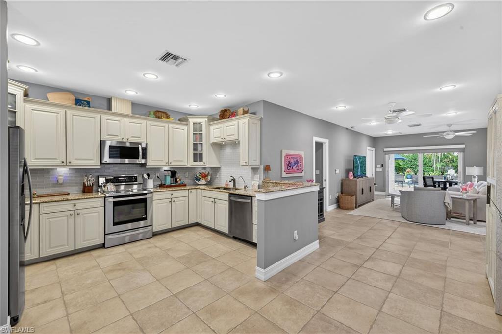 740 5th Avenue North Naples, FL 34102 - Photo 10 of 43 a large white kitchen with stainless steel appliances granite countertop a large counter top and a stove top oven