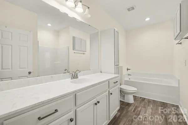 a bathroom with a double vanity sink a toilet and a bathtub
