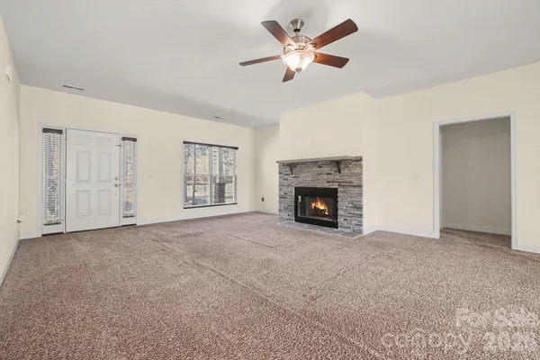 a view of an empty room with chandelier fan and fire place