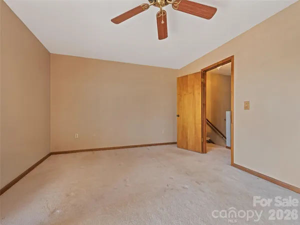 an empty room with a ceiling fan and window