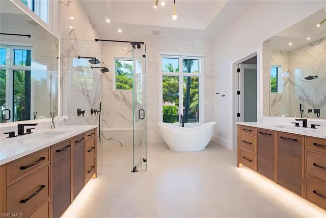 a spacious bathroom with a double vanity sink a large mirror and a bathtub