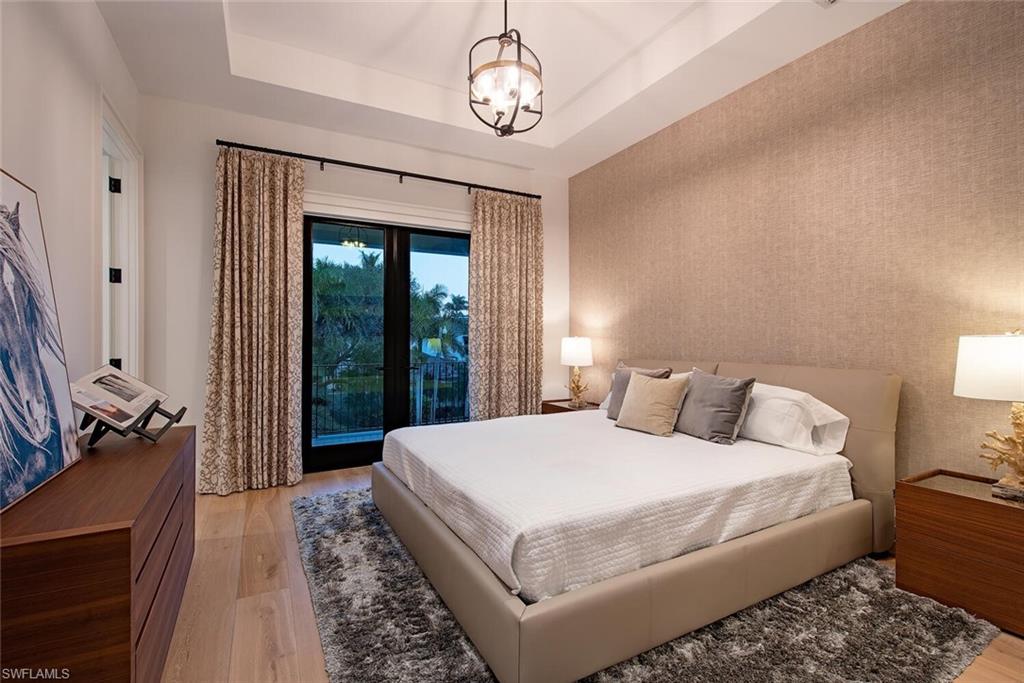 608 16th Avenue South Naples, FL 34102 - Photo 19 of 36 a bedroom with a large bed and a chandelier