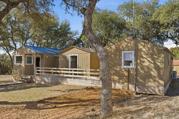 a view of a white house next to a yard with wooden fence