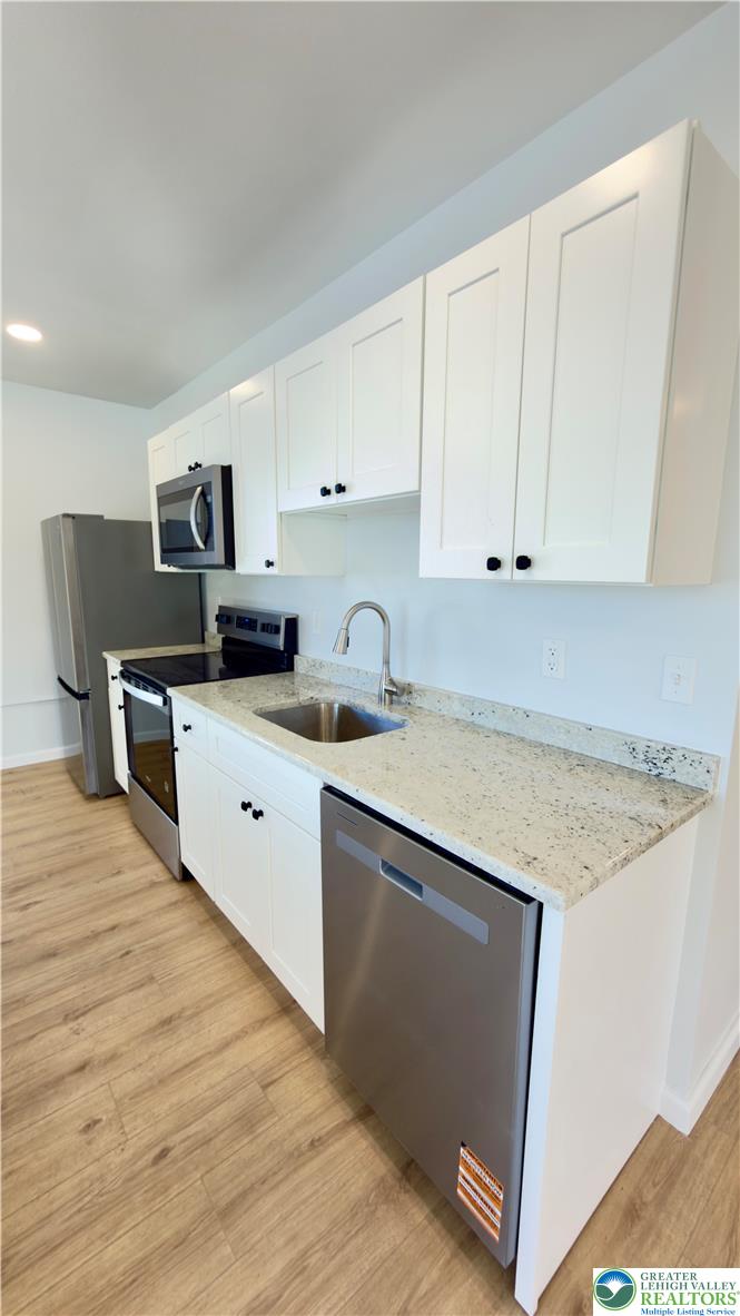 403 North Walnut Street, Unit B Bath, PA 18014 - Photo 11 of 31 a kitchen with stainless steel appliances granite countertop a sink dishwasher a stove top oven a refrigerator with white cabinets and wooden floor