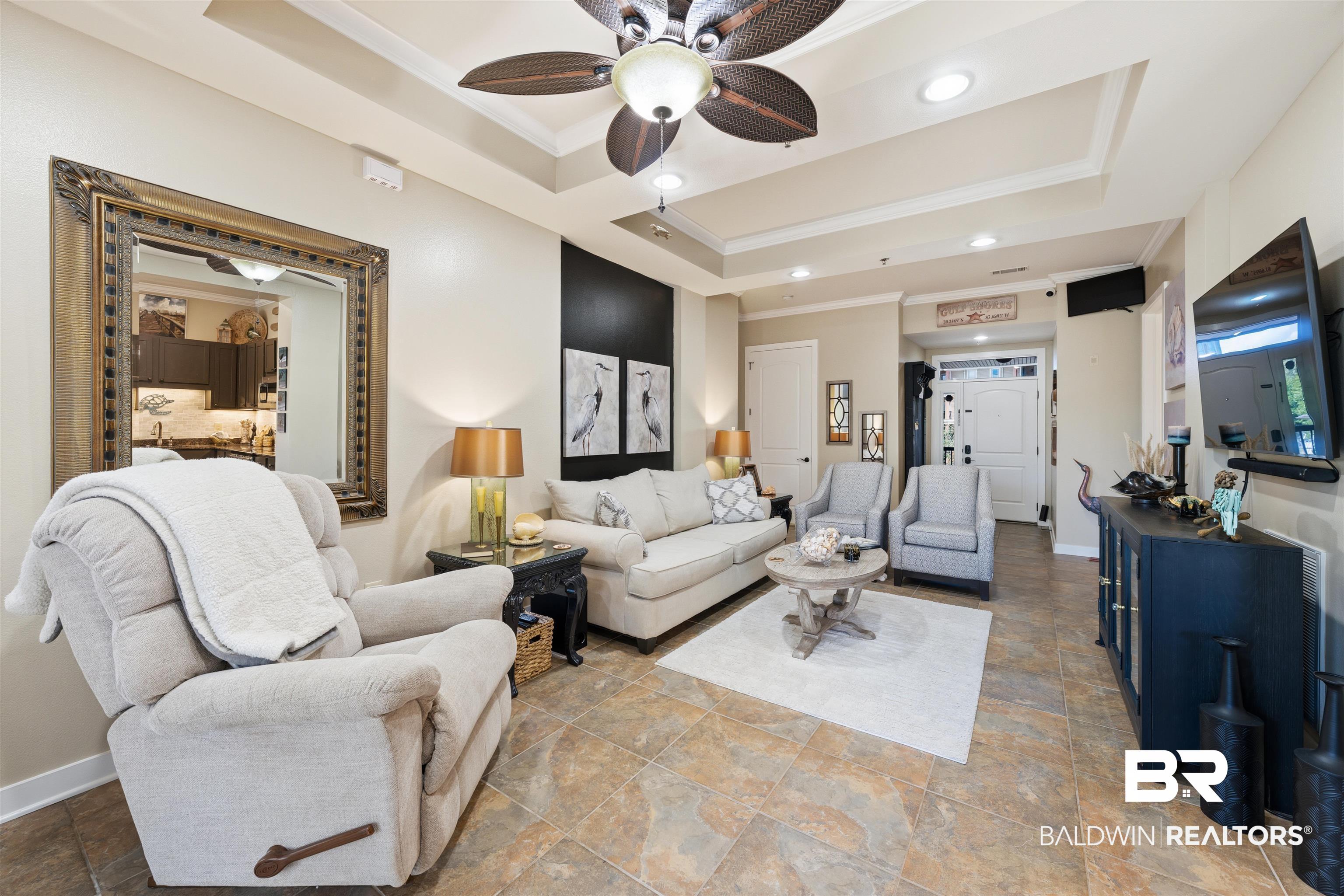1430 Regency Road, Unit H202 Gulf Shores, AL 36542 - Photo 18 of 25 Living area featuring stone finish flooring, a ceiling fan, ornamental molding, a raised ceiling, and recessed lighting