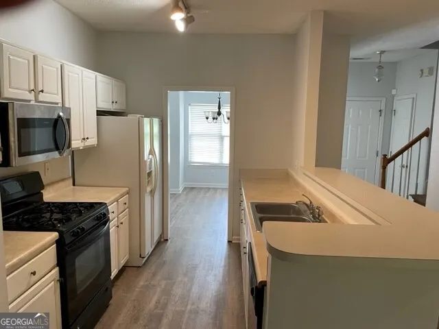 a kitchen with granite countertop a refrigerator stove and sink
