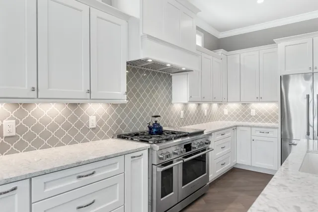 a kitchen with stainless steel appliances granite countertop a stove top oven a sink a dining table and chairs with wooden floor