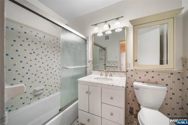a bathroom with a granite countertop sink a toilet a mirror and shower curtain