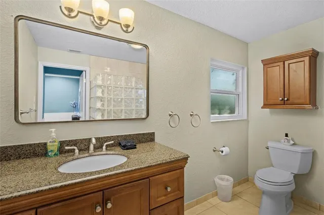 a bathroom with a granite countertop toilet a mirror and a sink