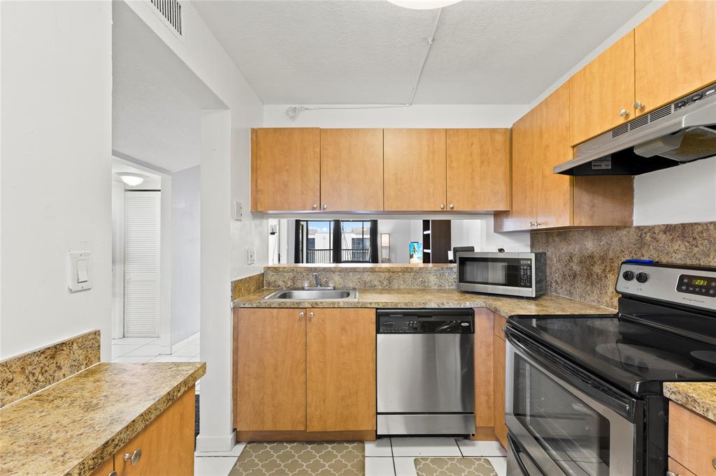 3199 Foxcroft Road, Unit 304 Miramar, FL 33025 - Photo 5 of 23 a kitchen with stainless steel appliances granite countertop a stove a sink and a microwave