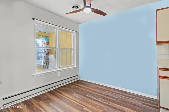 an empty room with wooden floor fan and windows