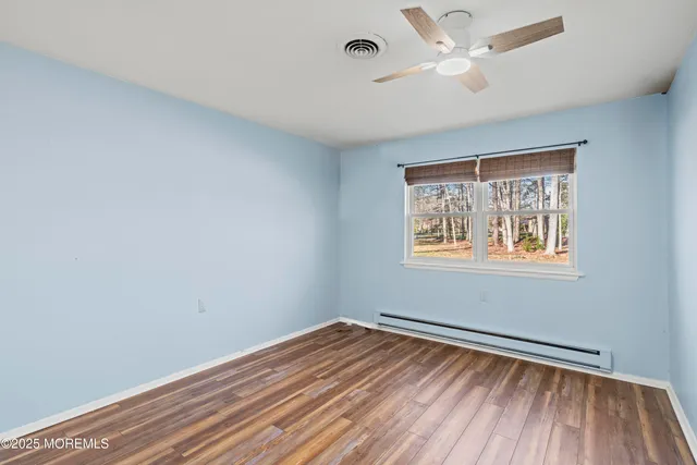 a view of empty room with wooden floor and fan