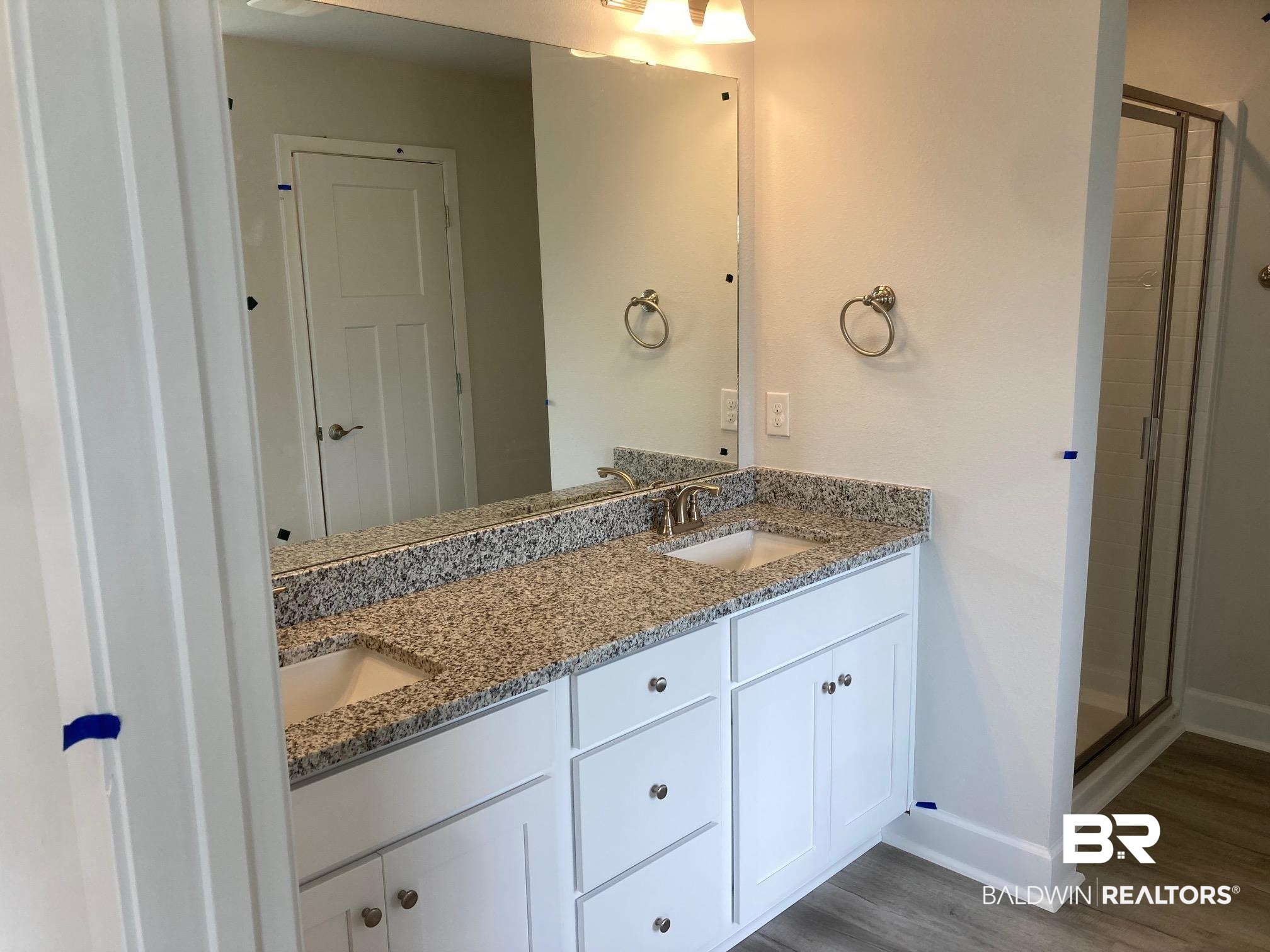 705 Mayflower Drive Foley, AL 36535 - Photo 10 of 19 Bathroom with double vanity, a sink, a shower stall, and wood finished floors