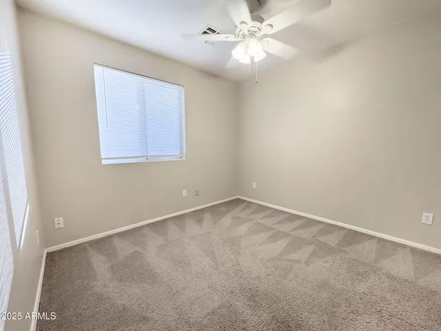 an empty room with a window and a fan
